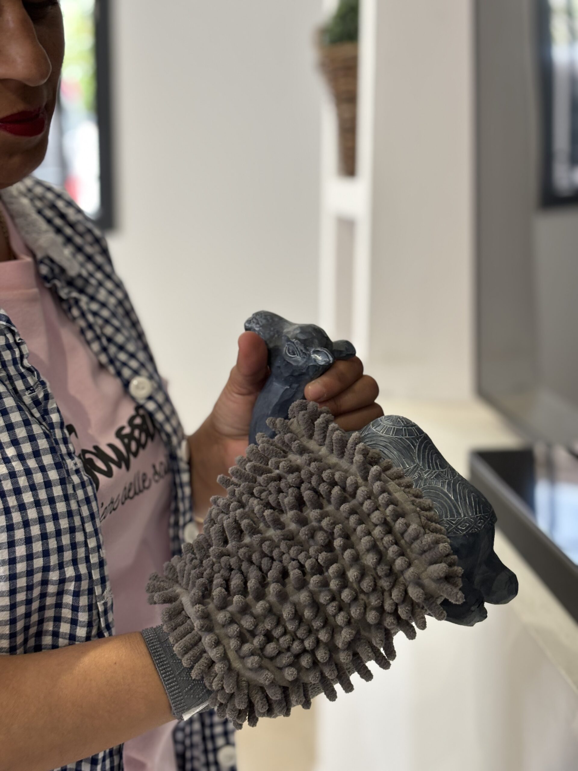 Gros plan sur une formatrice de la Soussou Academy utilisant un gant de nettoyage technique pour entretenir un objet de décoration, illustrant le contenu du Pack Découverte.